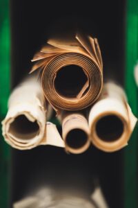 Rolled paper sheets stacked in a workshop setting, showcasing craftsmanship and industry.